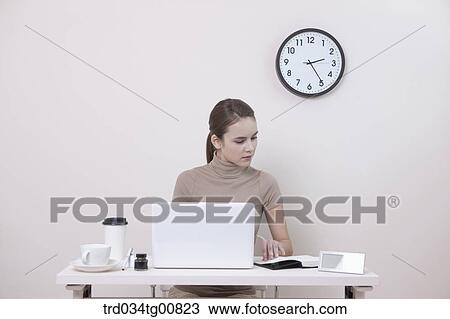 Stock Image - The woman looking at planner in the office. Fotosearch