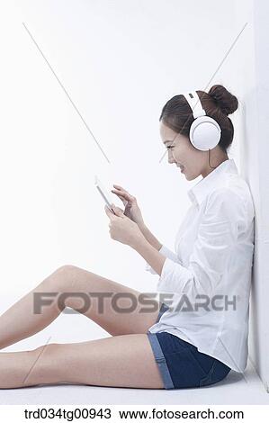 Stock Image - The woman looking at the CD with the headphone on . Fotosearch