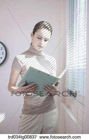 The woman looking at the document by the window View Large Photo Image Stock Photo - The woman looking at the document by the window. Fotosearch