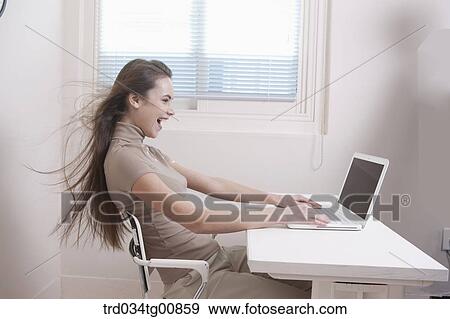 Stock Photo - The woman looking at the laptop with windblown hair. Fotosearch