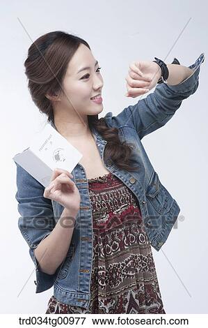 The woman looking at the watch with the passport in her hand View Large Photo Image Stock Photo - The woman looking at the watch with the passport in her hand. Fotosearch