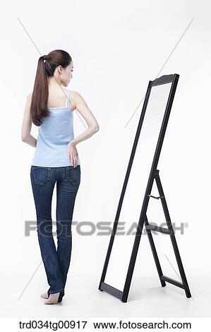 The woman looking her figure on the mirror View Large Photo Image Stock Photo - The woman looking her figure on the mirror. Fotosearch