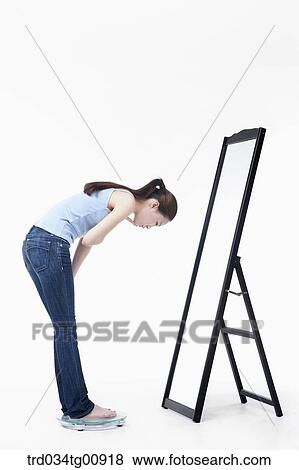 Stock Photo - The woman measuring her weight. Fotosearch