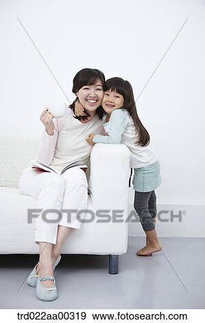 The woman on the couch and the girl hugging the woman View Large Photo Image Stock Photo - The woman on the couch and the girl hugging the woman. Fotosearch