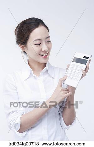Stock Photo - The woman putting button of calculator. Fotosearch