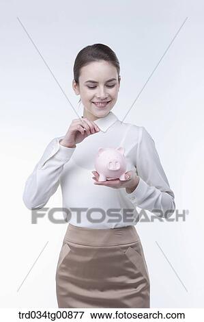 The woman putting coin into the piggy bank View Large Photo Image Stock Photo - The woman putting coin into the piggy bank. Fotosearch