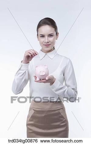 The woman putting coin into the piggy bank View Large Photo Image Stock Photograph - The woman putting coin into the piggy bank. Fotosearch