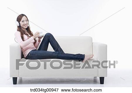 The woman reading the magazine on the couch with the headphone on View Large Photo Image Stock Photo - The woman reading the magazine on the couch with the headphone on . Fotosearch