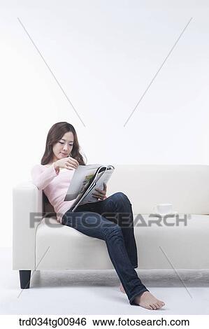 The woman reading the magazine on the couch View Large Photo Image Stock Photograph - The woman reading the magazine on the couch. Fotosearch