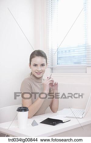 Picture - The woman sitting in front of the desk . Fotosearch
