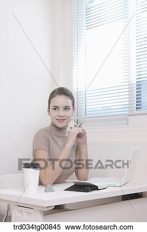 Stock Photography - The woman sitting in front of the desk . Fotosearch