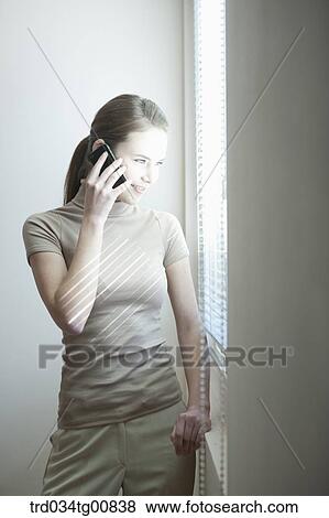 Stock Photo - The woman talking on the phone by the window. Fotosearch