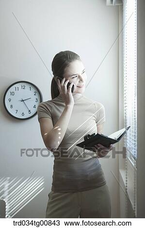Stock Image - The woman talking on the phone with the planner. Fotosearch