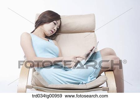 The woman touching tablet PC on the chair View Large Photo Image Stock Photo - The woman touching tablet PC on the chair. Fotosearch