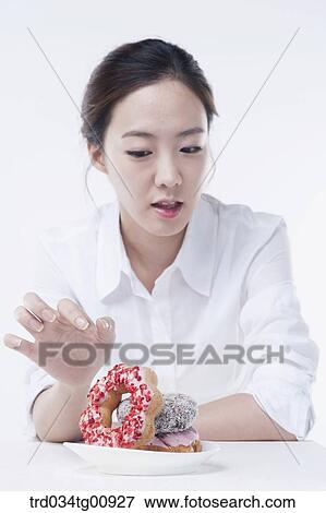 The woman trying to eat the doughnuts View Large Photo Image Stock Photo - The woman trying to eat the doughnuts. Fotosearch