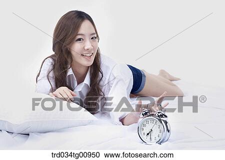 The woman turning off the clock on the bed View Large Photo Image Stock Image - The woman turning off the clock on the bed. Fotosearch