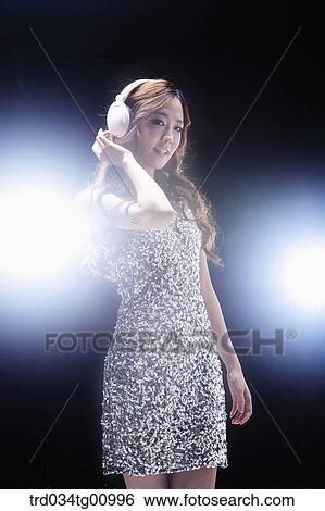 The woman wearing glittering dress with the headphone on View Large Photo Image Stock Photograph - The woman wearing glittering dress with the headphone on. Fotosearch