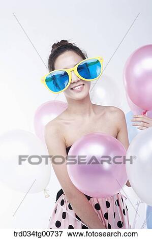 Stock Photo - The woman wearing party sunglasses with colorful balloons. Fotosearch