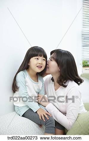 Stock Image - The woman whispering in girl's ear. Fotosearch