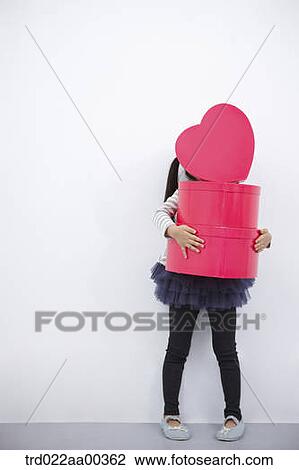 Stock Image - A girl holding red heart box. Fotosearch