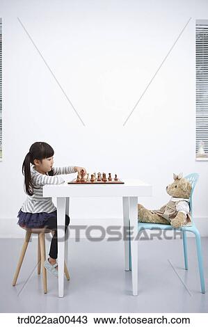 Stock Image - A girl playing chess game with teddy bear. Fotosearch