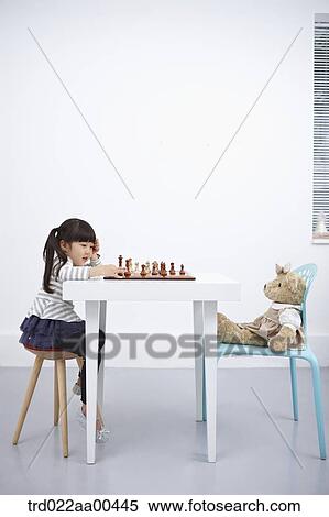 Stock Photography - A girl playing chess game with teddy bear. Fotosearch