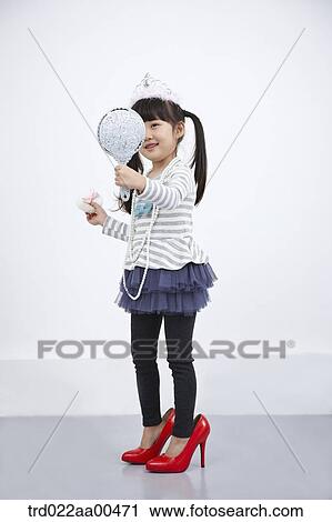Stock Image - A girl putting on make up while looking at mirror. Fotosearch