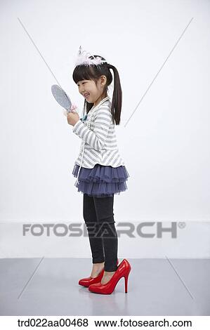 A girl putting on make up while looking at mirror View Large Photo Image Stock Photo - A girl putting on make up while looking at mirror. Fotosearch