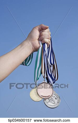 Stock Photo - A hand holding the prize medal. Fotosearch
