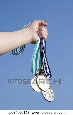 Stock Photo - A hand holding the prize medal. Fotosearch