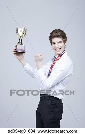 Picture - A man excited with the prize medal and trophy. Fotosearch
