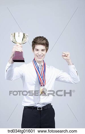 A man excited with the prize medal and trophy View Large Photo Image Stock Image - A man excited with the prize medal and trophy. Fotosearch