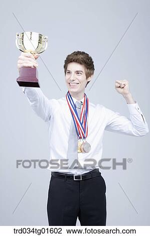 A man excited with the prize medal and trophy View Large Photo Image Stock Image - A man excited with the prize medal and trophy. Fotosearch