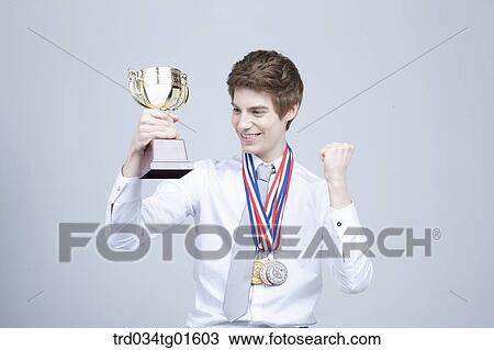 Stock Image - A man excited with the prize medal and trophy. Fotosearch