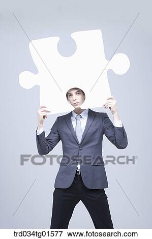 A man holding the big piece of white puzzle View Large Photo Image Stock Photo - A man holding the big piece of white puzzle. Fotosearch