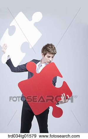 A man holding the big pieces of white and red puzzle View Large Photo Image Stock Photo - A man holding the big pieces of white and red puzzle. Fotosearch