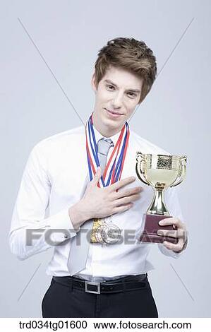 A man holding the prize medal and trophy View Large Photo Image Stock Image - A man holding the prize medal and trophy. Fotosearch