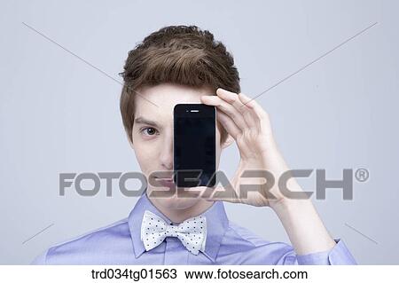 Stock Image - A man holding the smart phone over his face . Fotosearch