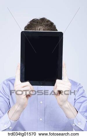 A man holding the tablet PC over his face View Large Photo Image Stock Image - A man holding the tablet PC over his face. Fotosearch