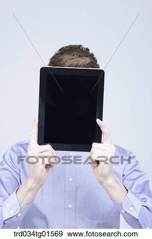 A man holding the tablet PC over his face View Large Photo Image Stock Photo - A man holding the tablet PC over his face. Fotosearch