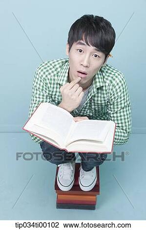 A man reading a book on the piled books View Large Photo Image Stock Image - A man reading a book on the piled books. Fotosearch