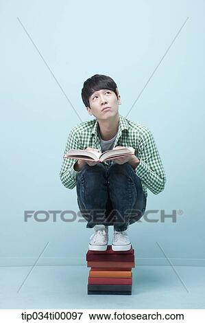 A man reading a book on the piled books View Large Photo Image Stock Photo - A man reading a book on the piled books. Fotosearch