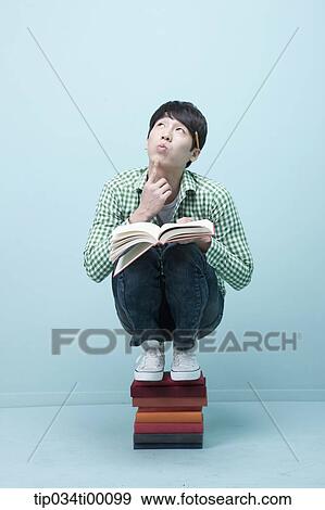A man reading a book on the piled books View Large Photo Image Stock Photo - A man reading a book on the piled books. Fotosearch