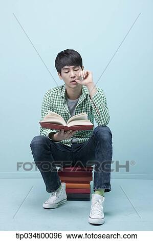 A man reading a book on the piled books View Large Photo Image Stock Photograph - A man reading a book on the piled books. Fotosearch