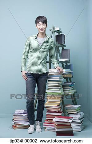 Stock Image - A man standing by colorful books and blue ladder. Fotosearch