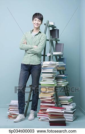 A man standing by colorful books and blue ladder View Large Photo Image Stock Image - A man standing by colorful books and blue ladder. Fotosearch