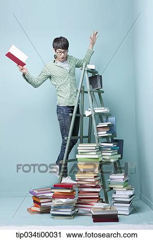 Stock Image - A man surprised at the piled books. Fotosearch