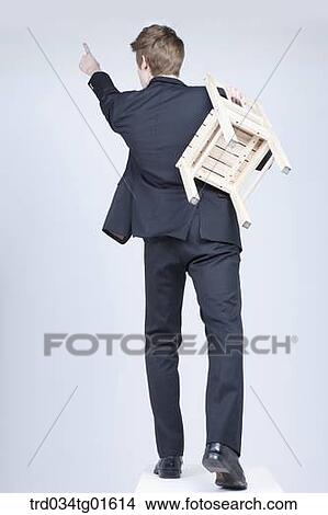 Picture - A man walking with the chair. Fotosearch