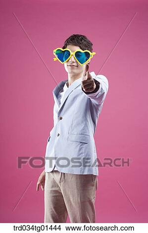 Picture - A man wearing the heart shaped glasses with pointing finger. Fotosearch