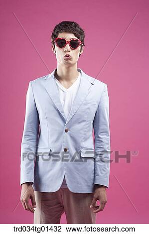 Stock Image - A man wearing the heart shaped glasses. Fotosearch